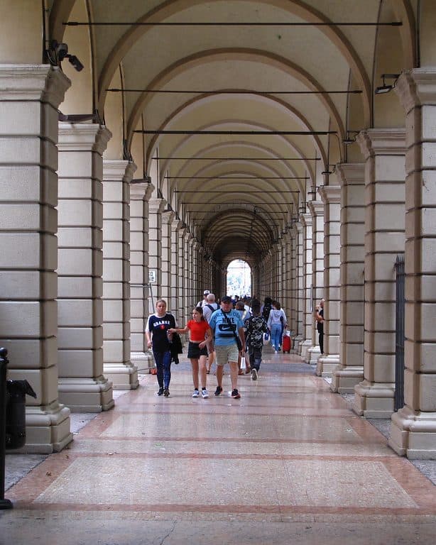 Bologna'da tarihi kemerli portikler altında yürüyen öğrenciler